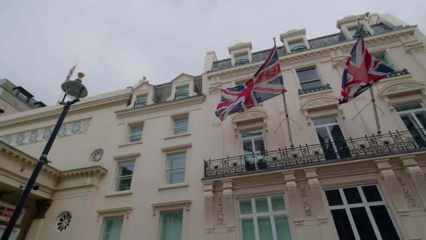 A cream colored building with british flags waving on the side