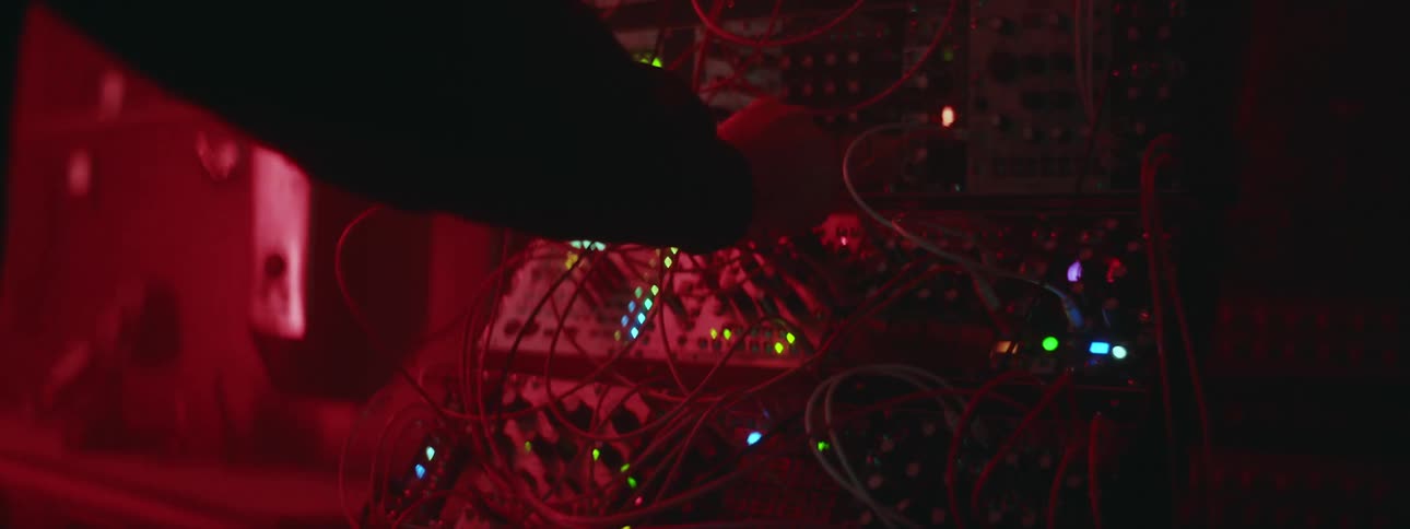 A man is standing at a computerized machine moving wires as colors lights glow