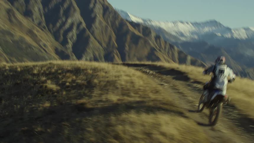 A man is riding a motorcycle through a mountain landscape