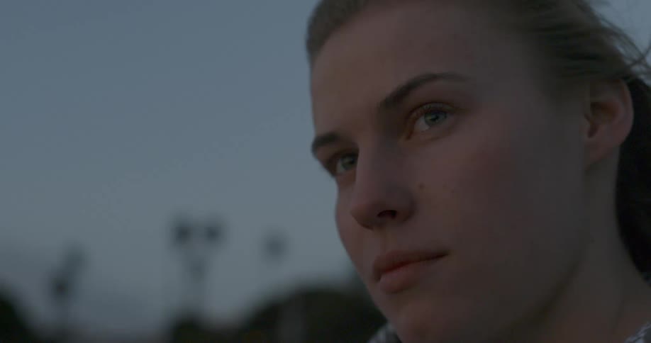 A woman is standing outside at dawn on a windy day