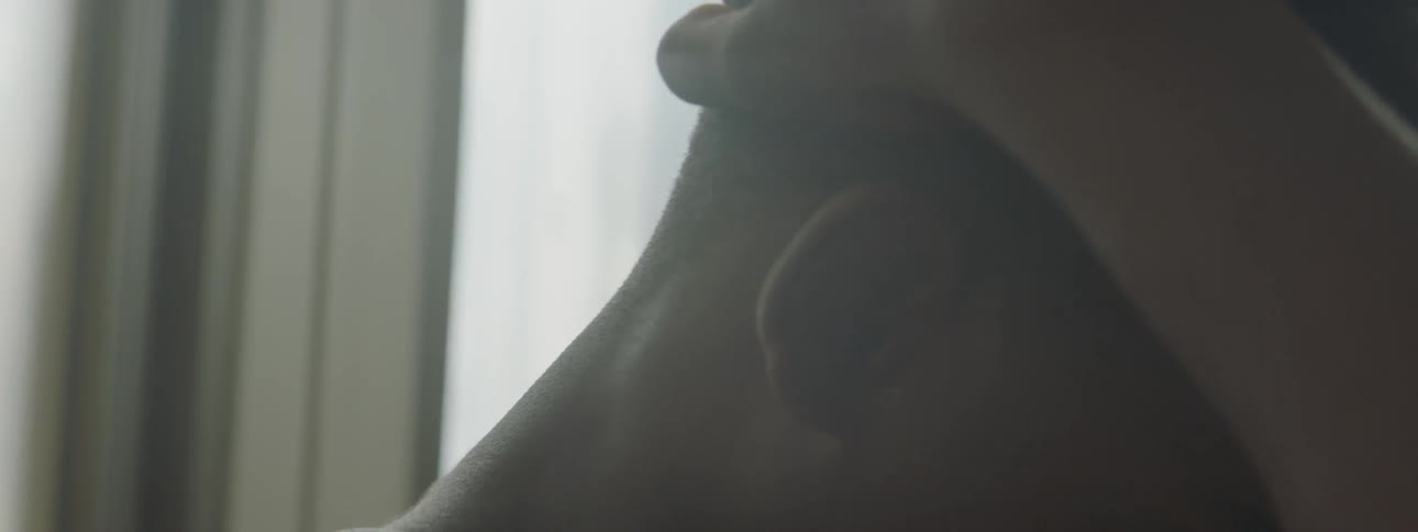 A boy is looking down by a window in a room