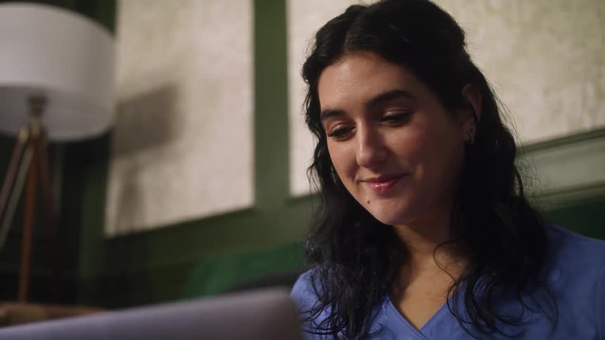 A woman sitting at home opens up her laptop
