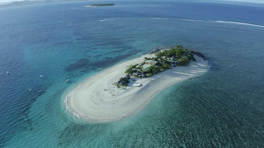 An aerial view of a beach house on a private island in the middle of the ocean