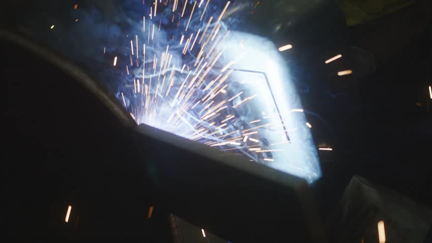 Sparks fly as metal is welded indoors