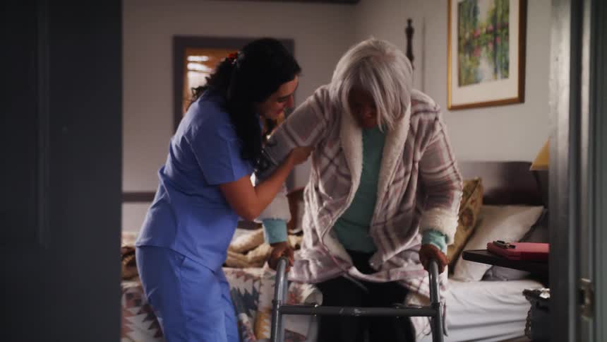 A nurse is helping an older elderly woman inside