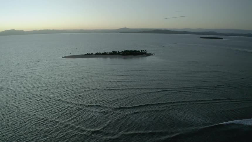 An aerial view revealing the ocean landscape with islands and mountains in the distance