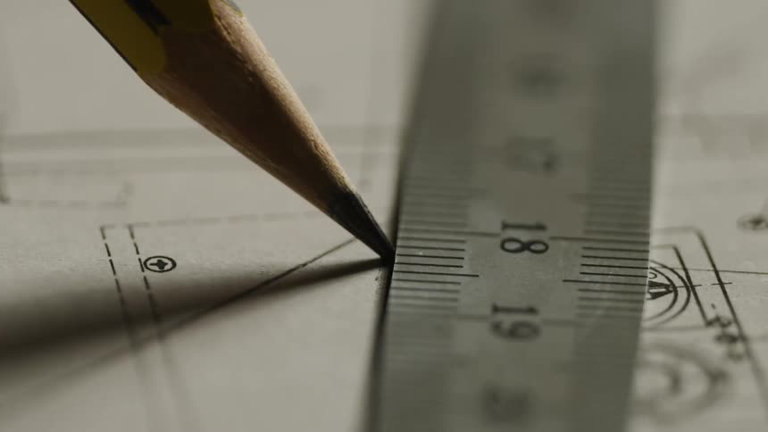 A person traces a line on blueprints