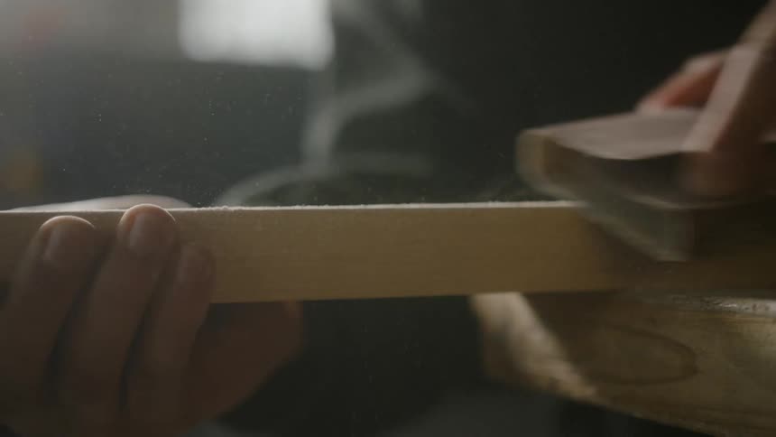 A man sanding a piece of wood