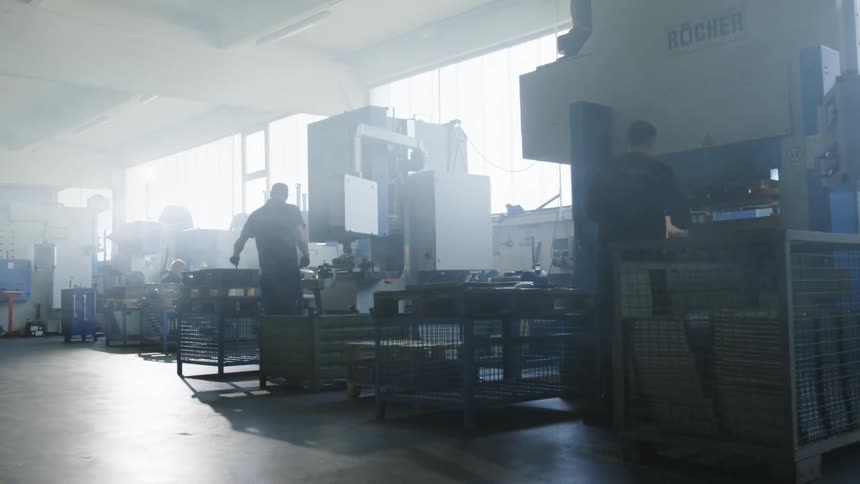 Two employees are working inside of a factory in the day time