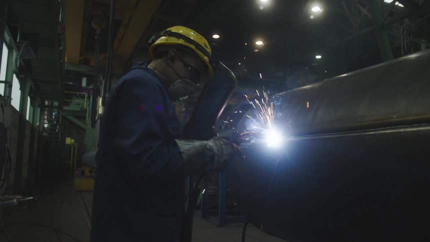 Factory worker welding a large metallic structure on a warehouse