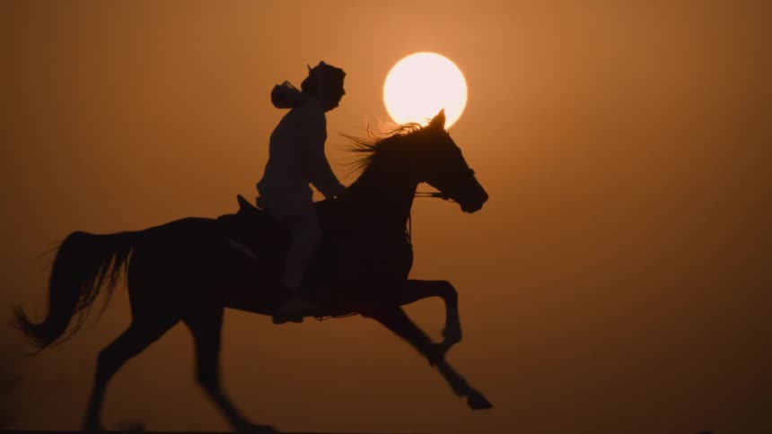 Silhouette of a person riding a horse at sunsets golden hour near a yellow bright sun