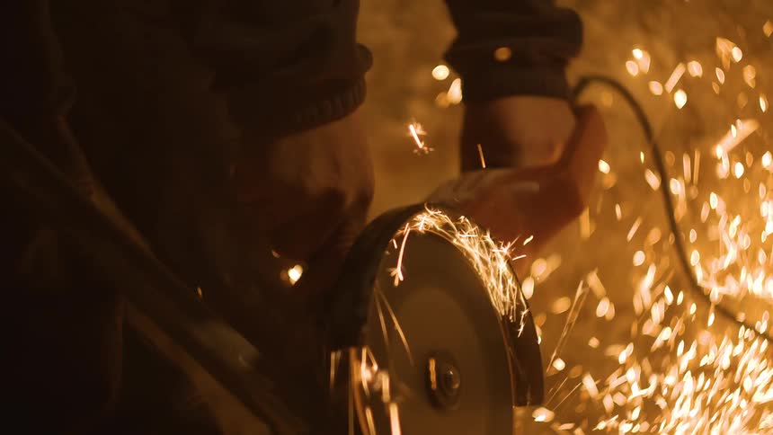 A person using a grinder creating sparks and flares