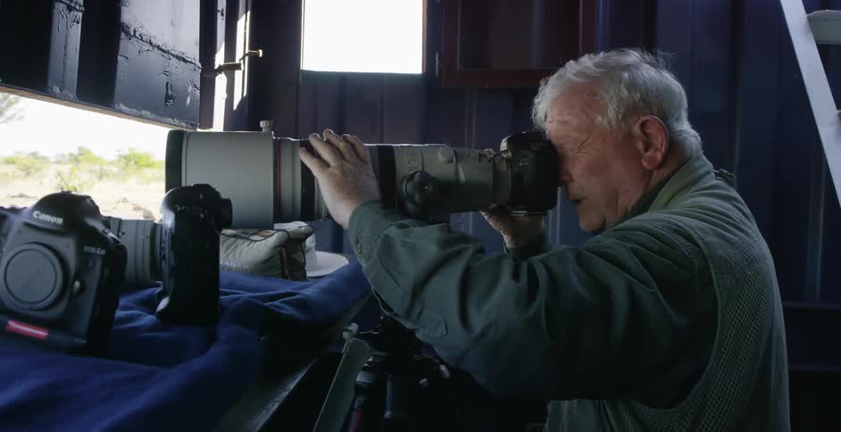 Elderly man adjusting his extremely large lens on a camera
