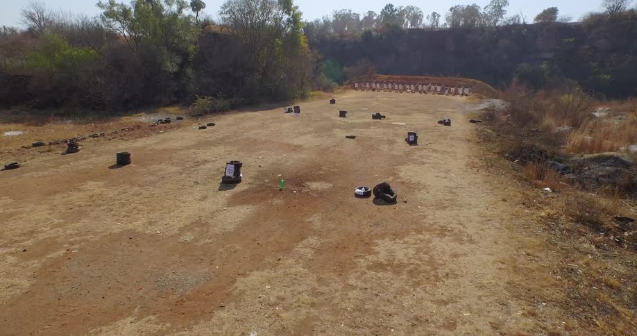 A plastic bottle filled with water explodes as something hits it on a shooting range