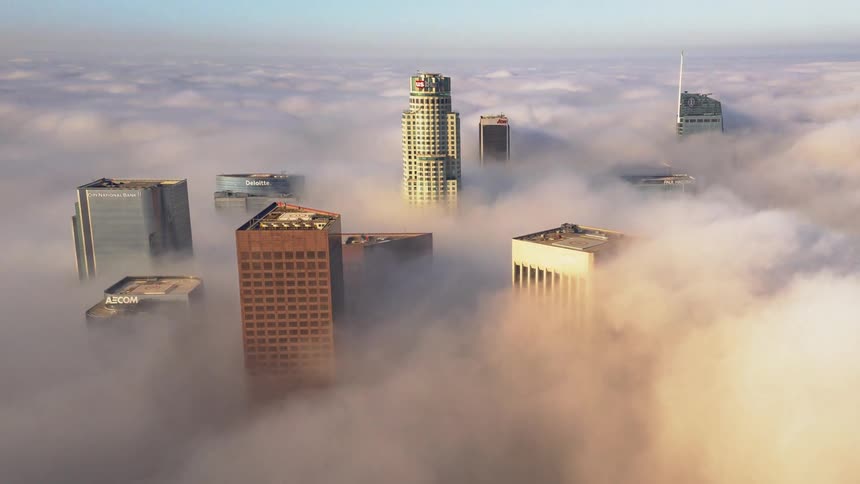 Dense clouds move around tall skyscrapers downtown