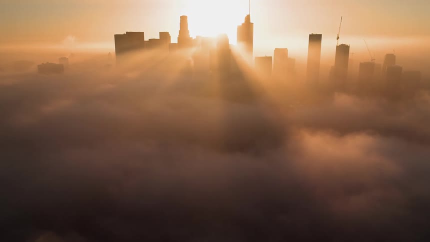 An aerial view of tall skyscrapers and clouds in a city at sunset