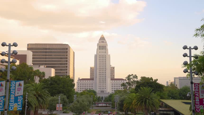 A tall white building with a center tower in the distance witha common square in front of it