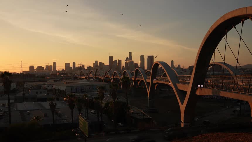 A landscape view of a arch bridge going into a dense city with tall buildings
