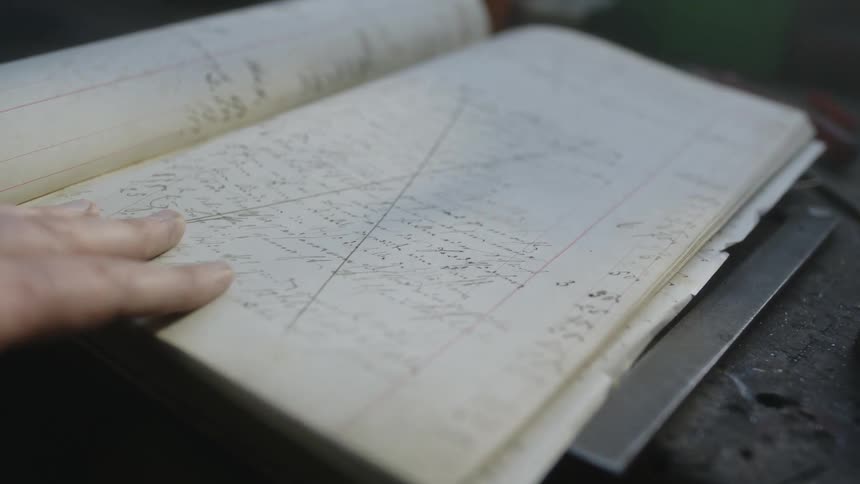 A man looks through a notebook with handwritten text