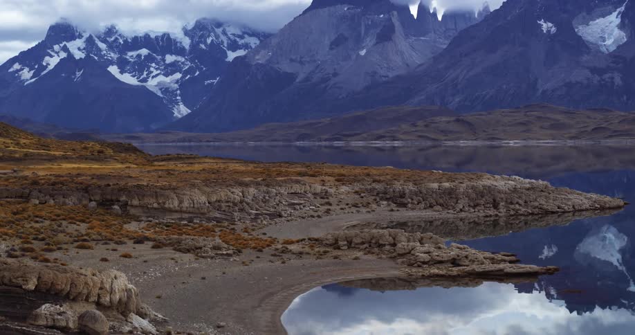 Snow capped mountains reflect on a lake below