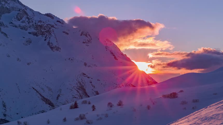 The sun setting over snowy mountains in nature