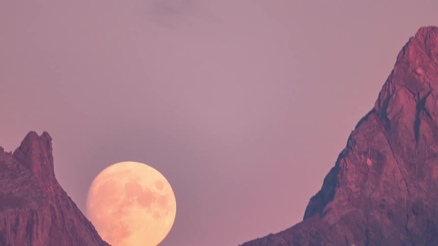 The moon is rising over the mountains