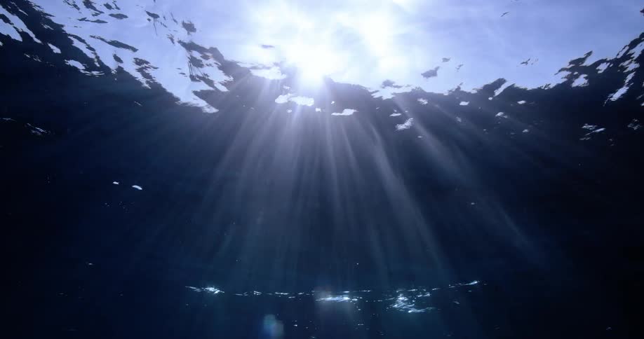 Sunlight reflecting through the ocean surface shining rays of light through the waves