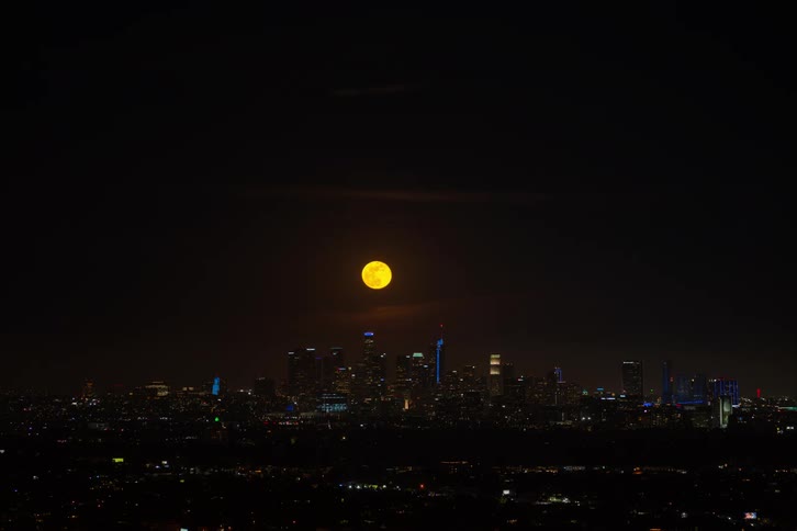 A time lapse of a moon rising over a city at night