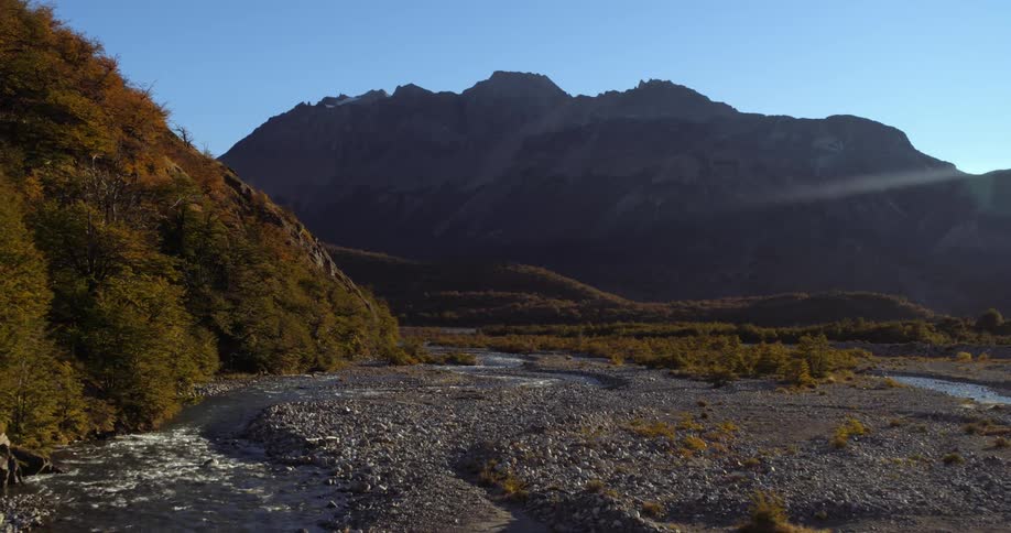 Aerial view of a river flowing in the wilderness close to the mountains at morning