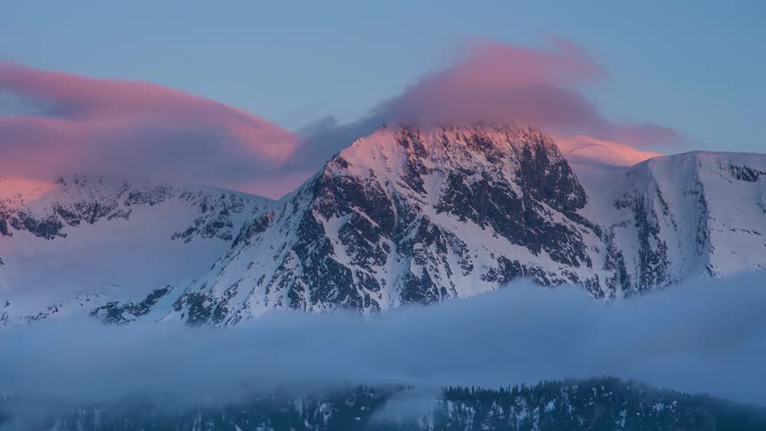 Clouds flow over the snow covered mountain