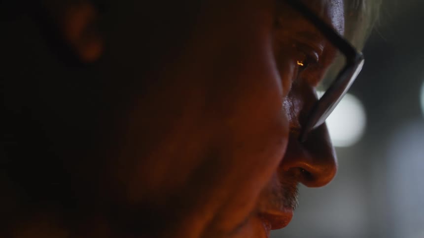 A close up of a mans face wearing glasses looking intently in front of him