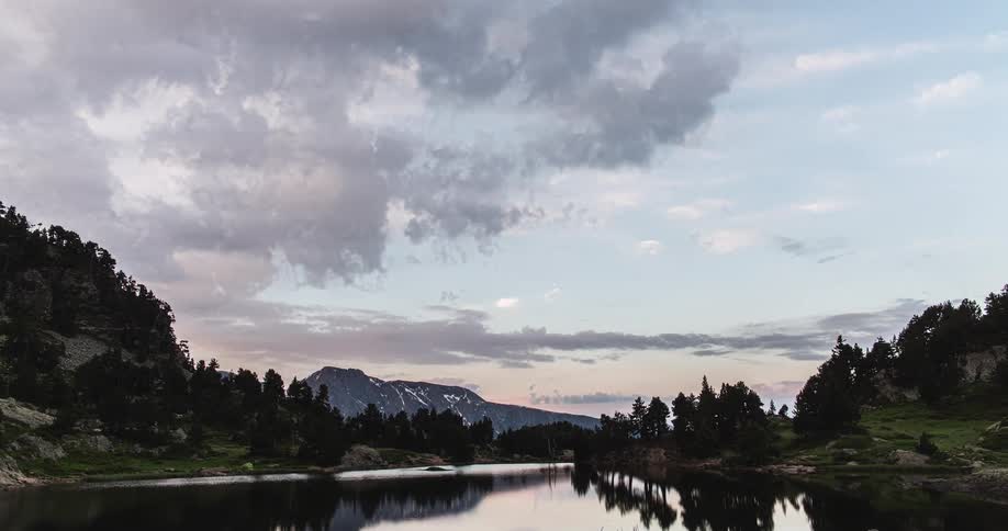 Time lapse footage of clouds rolling over a river in the mountains at evening