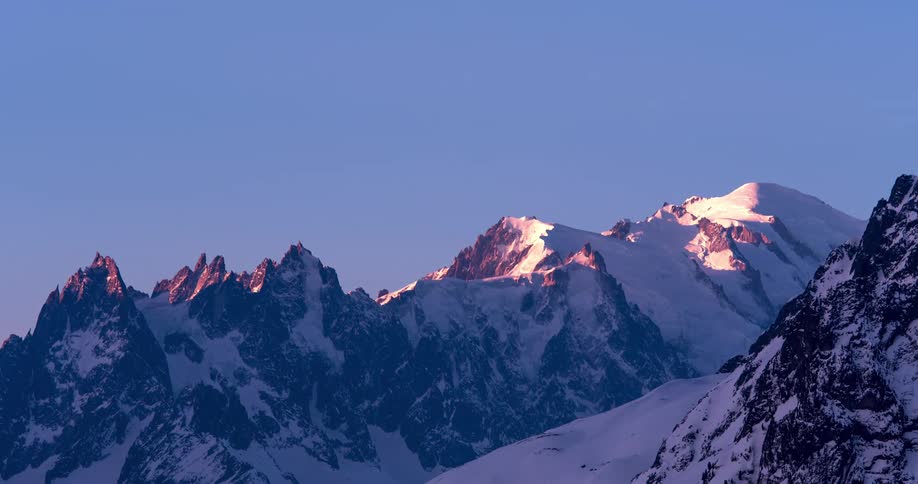 Sunlight on snow covered mountains tints red briefly