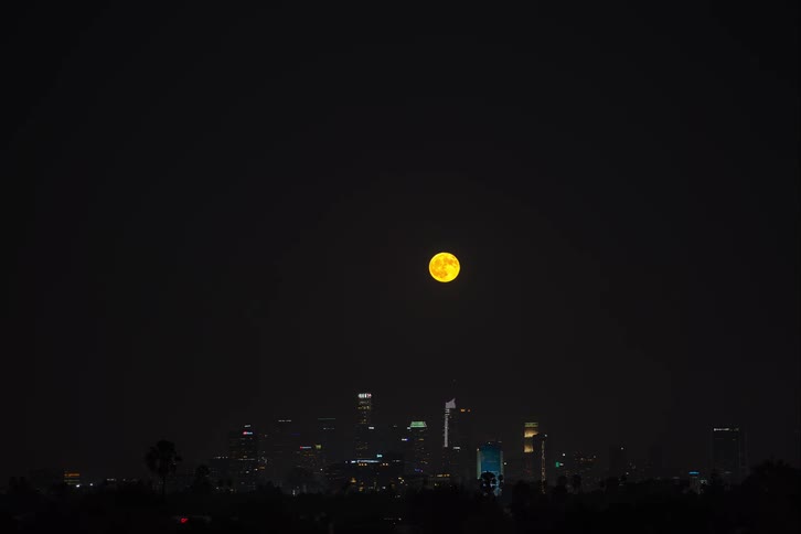 Time lapse of the full moon rising over the city skyline at night