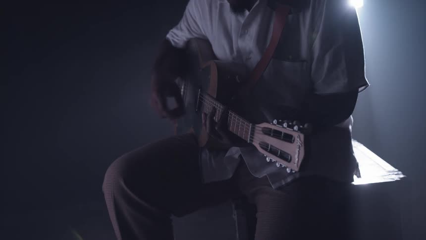 A man is playing guitar under a spotlight