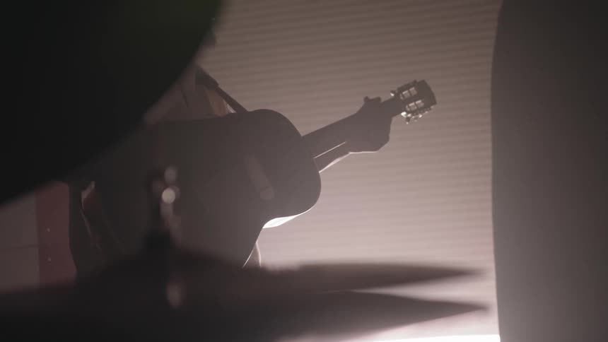 A man is playing guitar near some drums