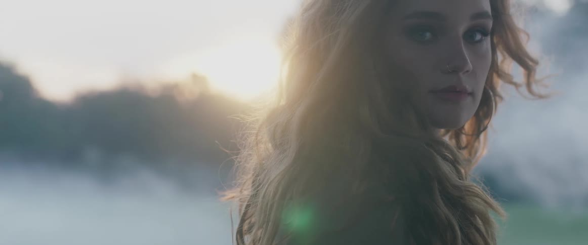 A young caucasian woman with long curly hair standing in the sunset