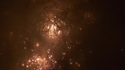 Sparks fly from an explosion underwater in the dark