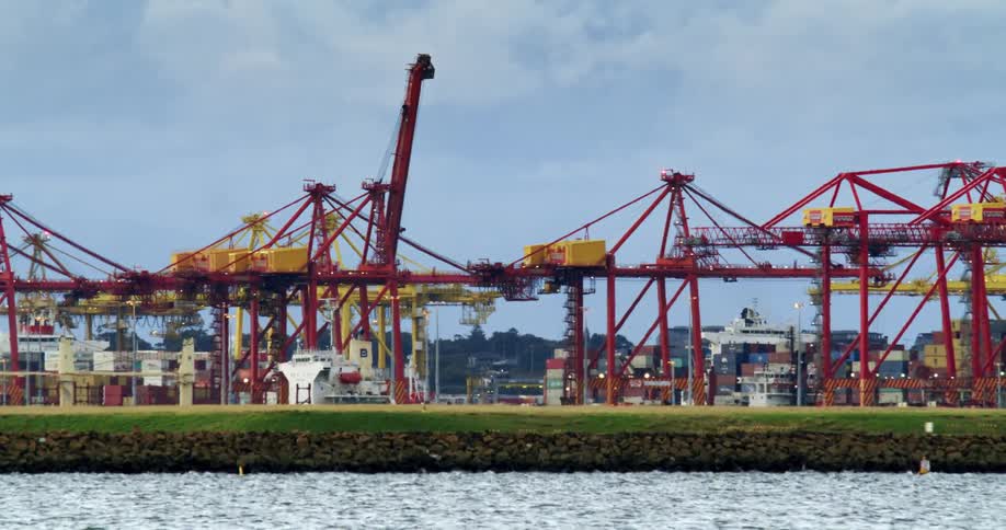 Footage of the cranes and structures of a shipping harbor near the coast