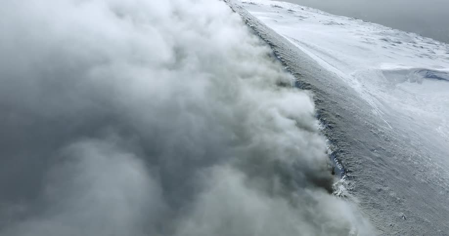 An aerial view of a snowy mountain landscape with clouds