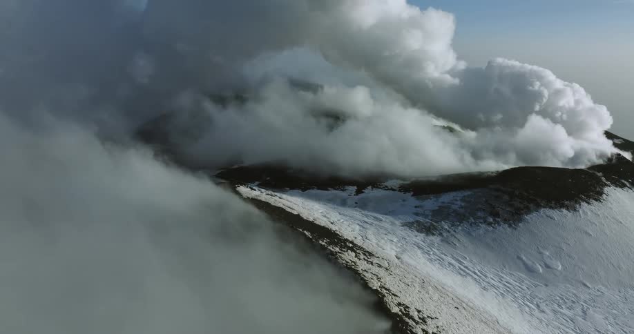 An aerial view of a snowy mountain landscape with clouds