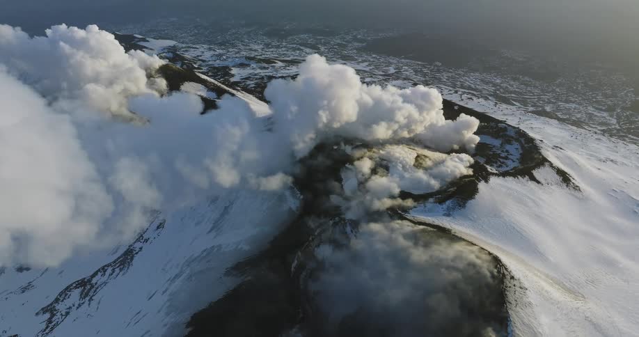 Smoke rises from a snow capped volcano
