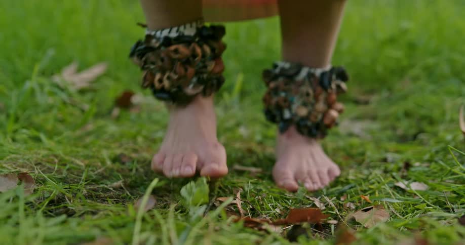 A close shot of a dancers feet bands with shells are worn around ankles