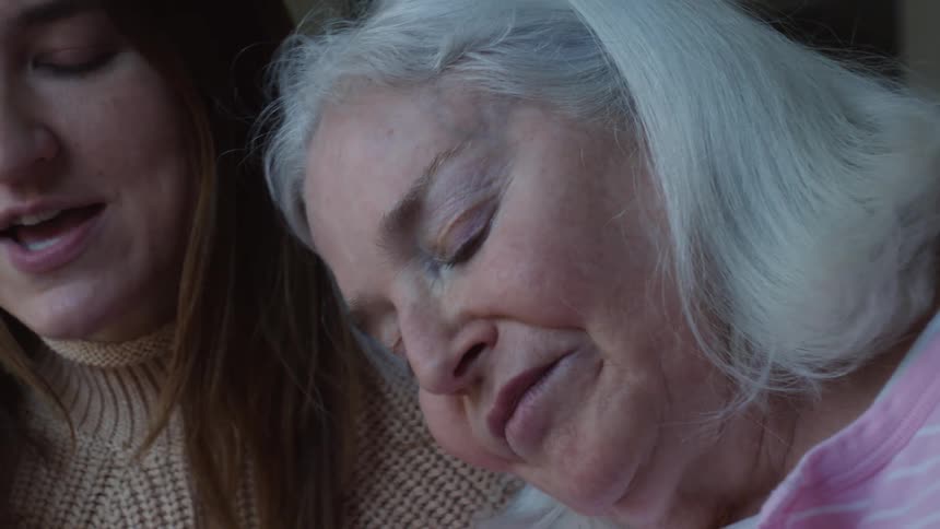 A woman rests her head on her granddaughters shoulder