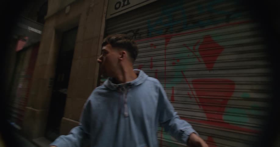 Young man carries a skateboard on his hands while walking on an alley in the city