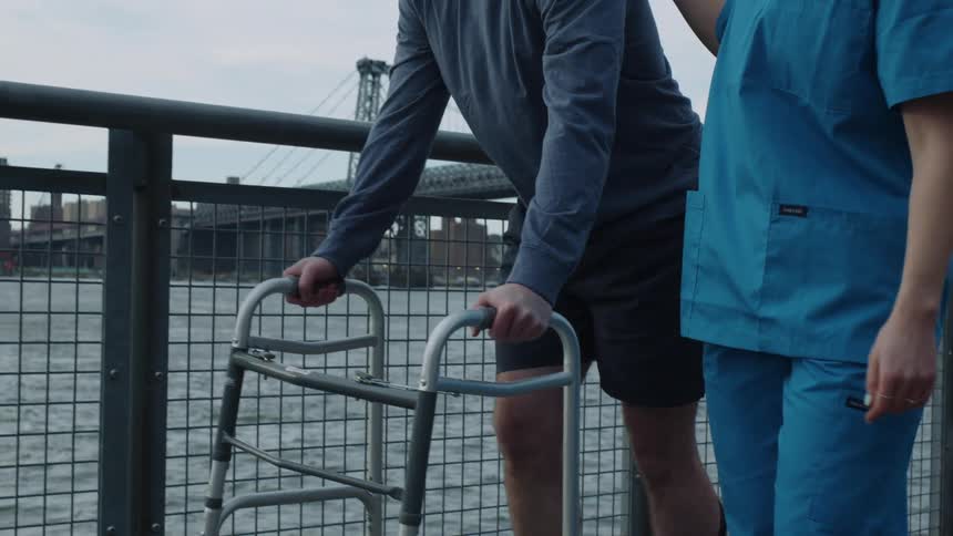 A physical therapist helps a man with a walker