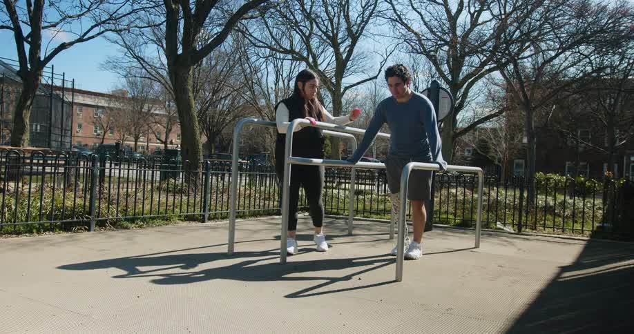 A young woman is helping this man walk outdoors
