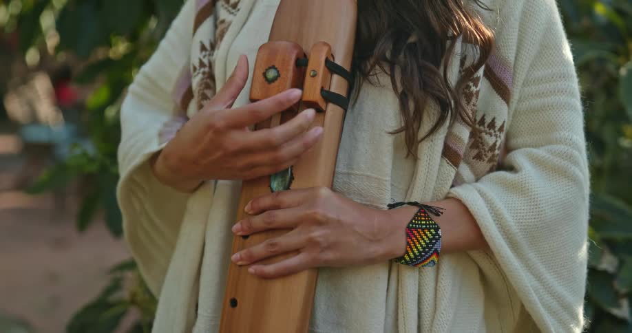 Woman standing outdoors adjusts flat wooden flute