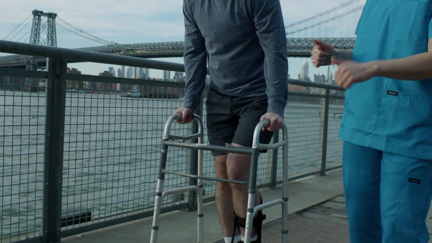 A man is walking with a walker by the water