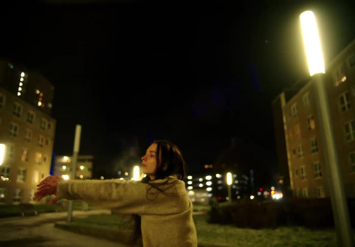 A woman is dancing by the apartment buildings